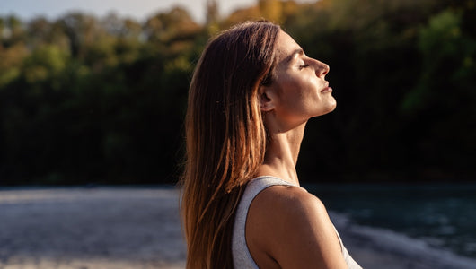 Woman with her face turned to the sun while considering the difference between red light therapy vs sunlight